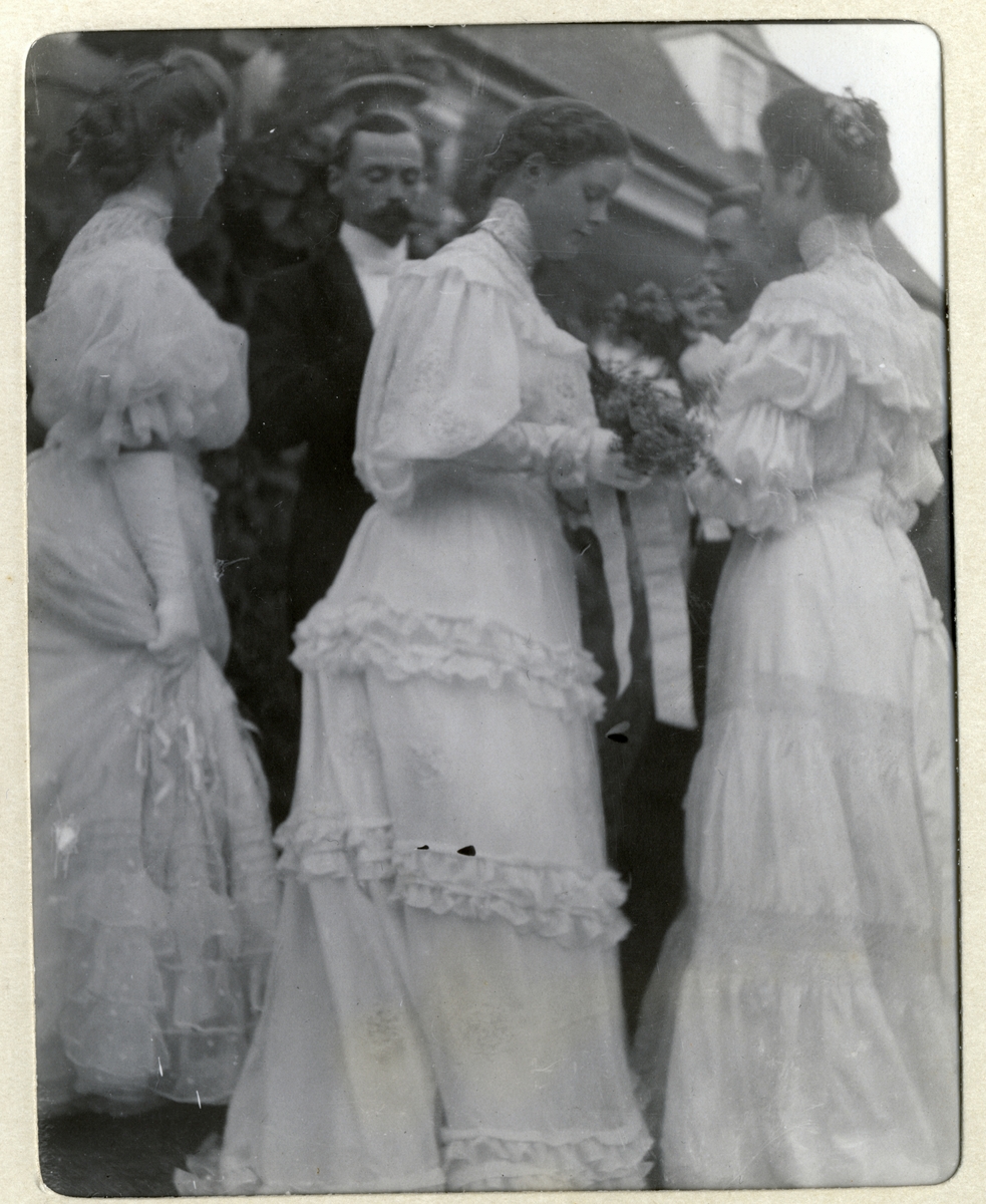 Bryllup på Bogstad gård. Nini Wedel Jarlsberg og Westye Parr Egeberg gifter seg. Fem bryllupsgjester, tre kvinner(brudepiker?) og to menn, i samtale på trappen. Fotografert 17.09.1904.