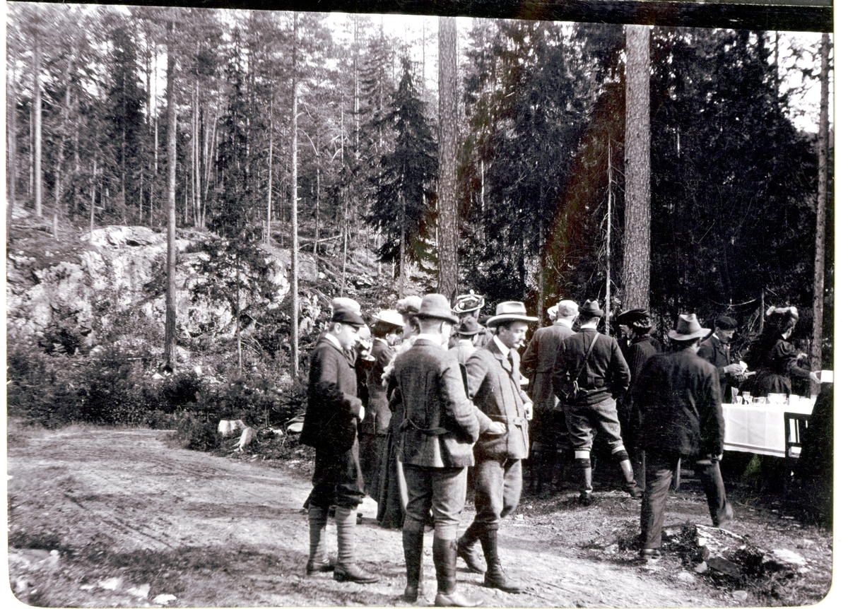 Elgjegere med følge på vei til spisepause i det fri under elgjakten på Fossum gård i Bærum(?). Fotografert september 1905.