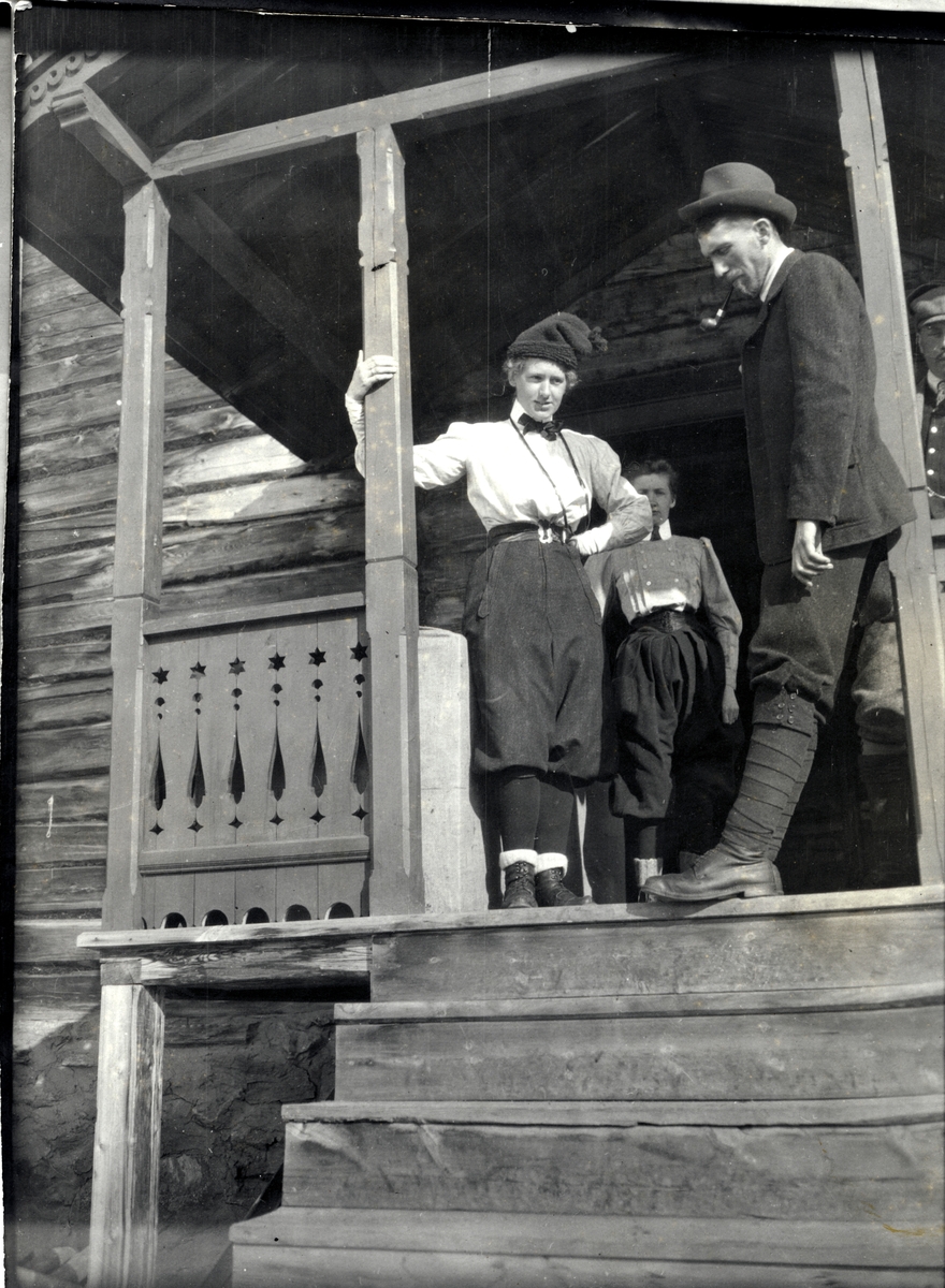To kvinnelige og en mannlig skiturist i inngangspartiet på hytte i Sikkilsdalen i Nord-Fron. Fotografert påsken 1905.