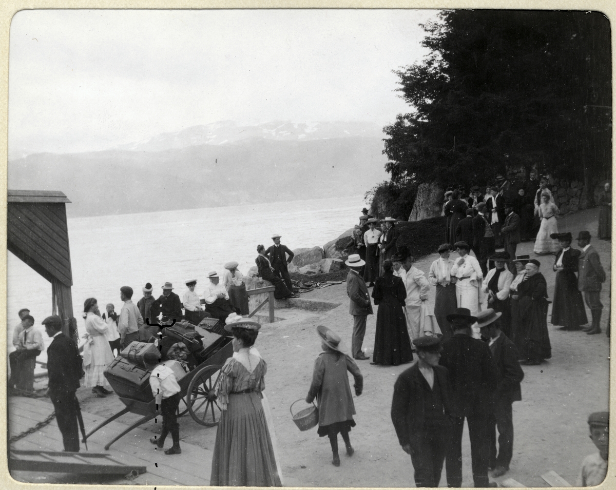 Fra bryggen i Balestrand, Sogn og Fjordane. Midt på bildet tar Herman og Mathilde Wedel Jarlsberg avskjed med Nini og Westye Egeberg som skal reise med "MS Kommandøren" til Gudvangen. Fotografert 1906.