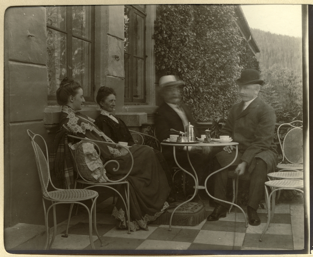 Nini og Westye Egeberg drikker kaffe på verandaen til Bogstad gård sammen med Ninis foreldre, Mathilde og Herman Wedel Jarlsberg. Fotografert forsommeren 1907.