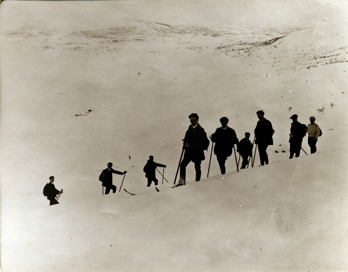 Ni skigåere på vei opp Veslefjell, høyeste punkt på Besseggen, på vei til Bessheim i Jotunheimen. Fotografert i mars 1908.