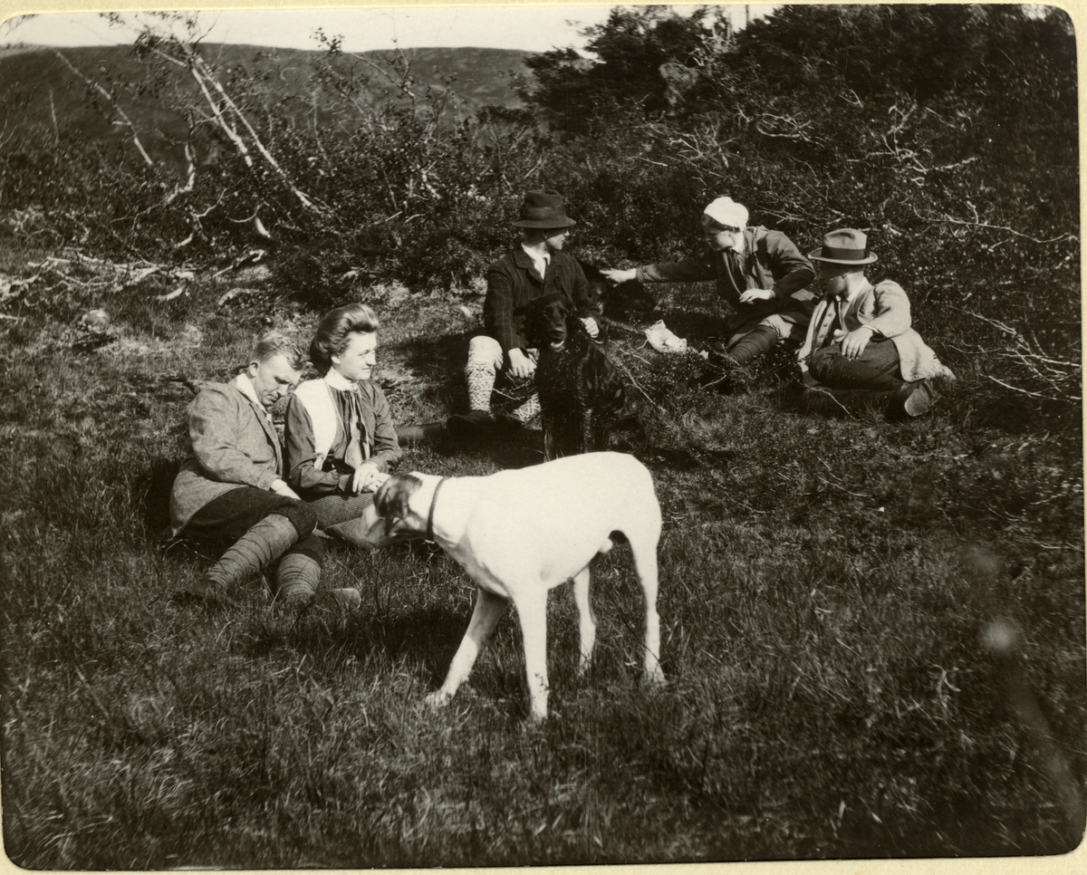 Jaktlag, bestående av to kvinner og tre menn samt en hund, raster under rypejakten ved innsjøen Langen i Nord-Trøndelag. Til venstre antagelig Carlos og Ellen Jakhelln. Fotografert 1910.