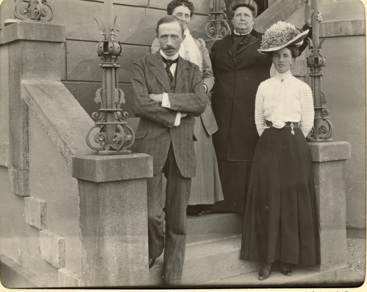 Fire kvinner og en mann på trappen til inngangspartiet på Bogstad gård. Bak Mimi Wedel Jarlsberg og Edle Wedel Jarlsberg, foran Antonio Borgiano og Nini Egeberg. Fotografert august 1911.