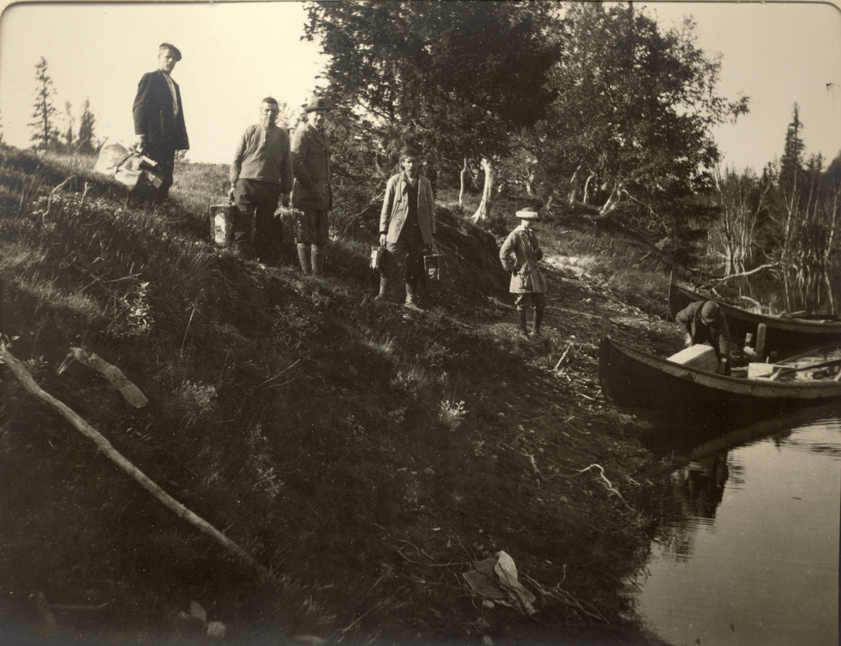 En gruppe av jegere og medhjelpere forbereder avreise i båt på Fjergen fra jakthytten i Øst-Fjergen, Trøndelag. Fotografert 1913.