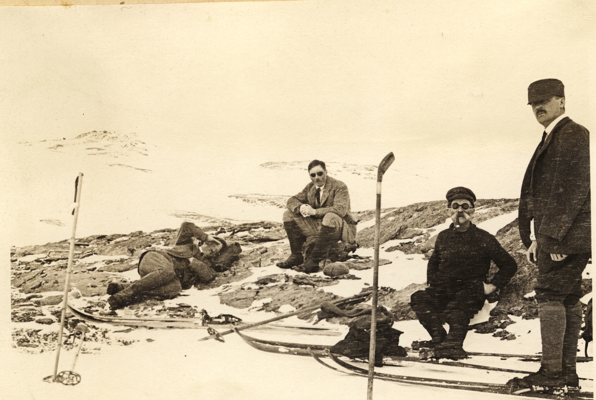 Fire skigåere raster på vei fra Finse over Hardangerjøkulen til Demmevasshytta i mars 1916. Fra venstre Westye P. Egeberg, Fritz T. Hakestad, ukjent (turistfører?) og Anders Beer. 