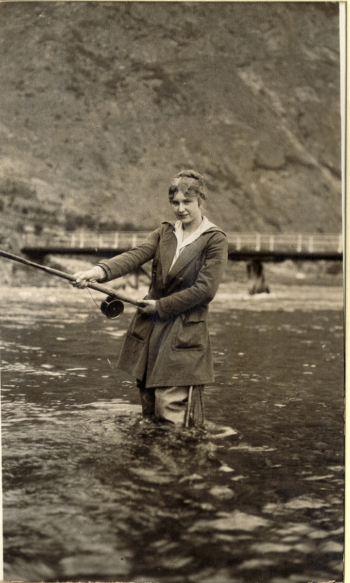 Evelyn Egeberg på fluefiske i Lærdalselvi, Sogn og Fjordane. I bakgrunnen en bro over elven. Fotografert sommeren 1916.