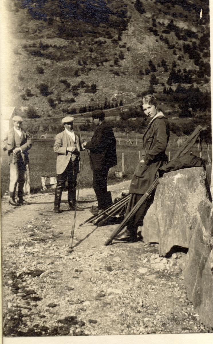 Fire laksefiskere med fiskeutstyr, på fiskeplass ved Lærdalselvi. Fra venstre antagelig Waldemar Kallevig, Westye P. Egeberg, en klepper og Evelyn Egeberg. Fotografert 1916.