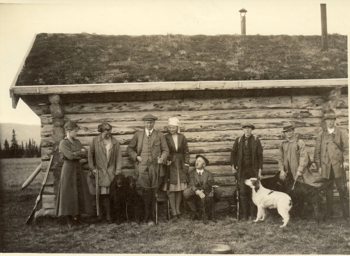 Jaktlag og hjelpere foran gammel jakthytte ved Øst-Fjergen, Meråker. Fra venstre Ingeborg Fearnley, , Ellen og Carlos Jakhelln, Vera Kallevig, Westye Egeberg, to "rypegutter" og en jeger. Fotografert 1916.