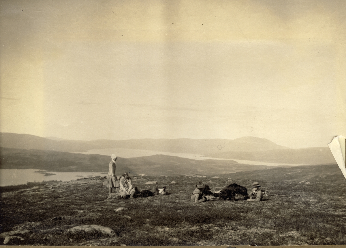 Et jaktlag hviler i Meråker, med utsikt til innsjøene Langen og Feren. De to kvinnene er antagelig Vera Kallevig og Ellen Jakhelln. Fotografert 1916.