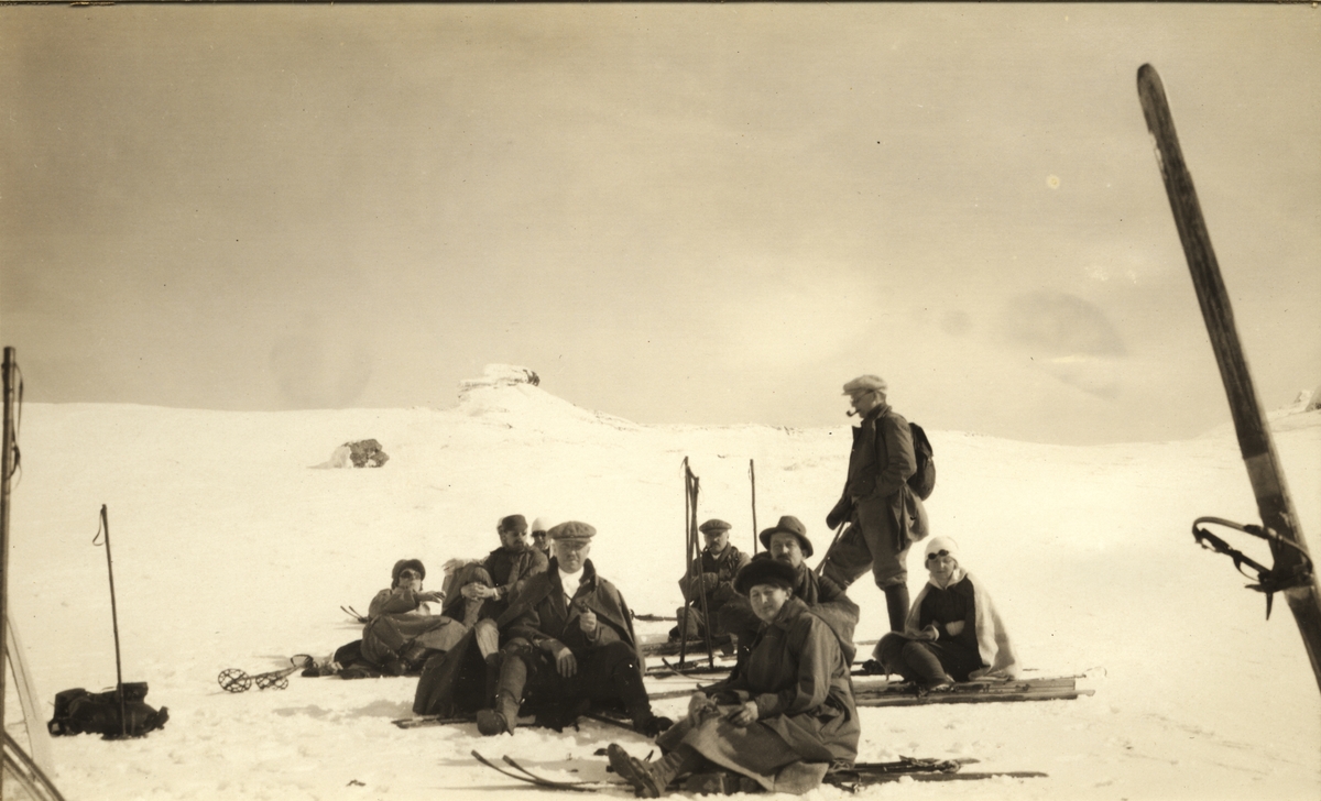 En gruppe kvinnelige og mannlige skigåere raster ved Finse. Fotografert 1920.