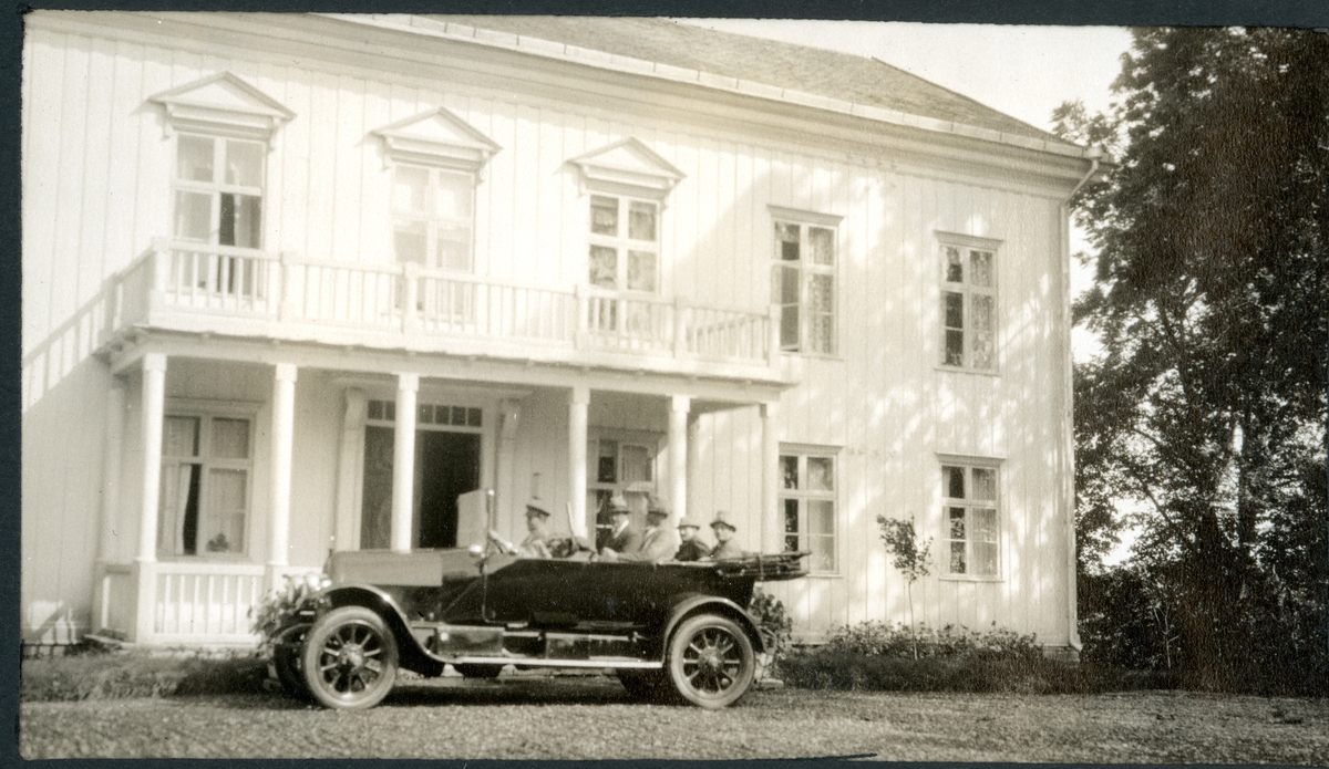 Tom Fearnley, Nils O.Y. Fearnley, Johan Collett og Westye P. Egeberg sitter i bil med sjåfør, antagelig Kristian Skuggen, foran inngangspartiet til Tom Fearnleys gods Rosenborg i Wärmlandsnes i Sverige. Fotografert 1924.