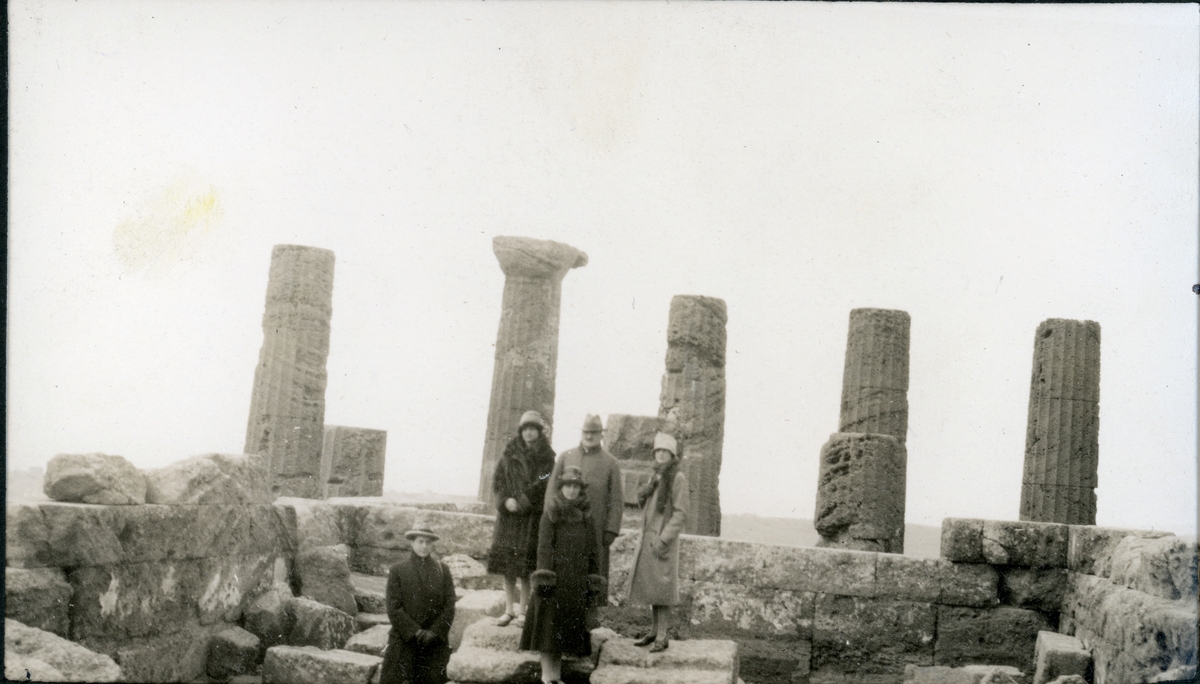 Et reisefølge står i ruinene etter et tempel i Girgenti på Sicilia. Foran fra venstre antagelig Anton Fredrik Klaveness, Lucy Egeberg og Nini Egeberg. Bak et ukjent par. Fotografert under familien Egebergs reise i januar 1927.