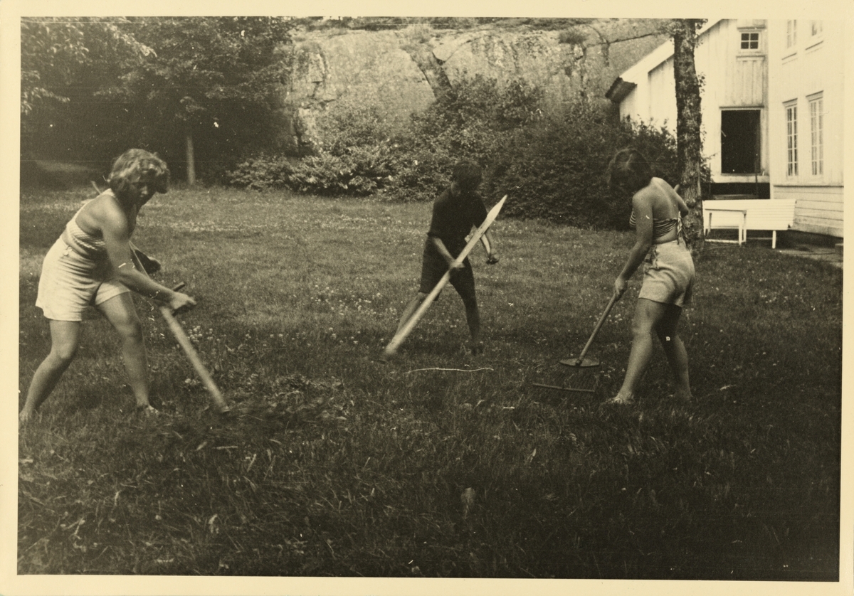 Tre ungdommer, hvorav den ene er Lucy Hansson, driver slått på tunet i Dannevigen. Fotografert 1944.