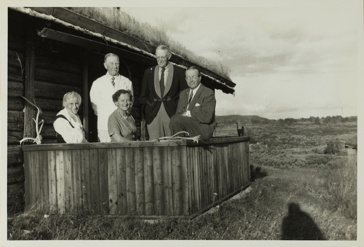 To kvinner og tre menn på hytteveranda, antagelig ved Revsjøen i Gausdal, Oppland. Fra venstre Olivia Hansen, Westye Parr Egeberg, Henny Løvenskiold, Aksel Hansen og Carl Otto Løvenskiold. Fotografert 1953.