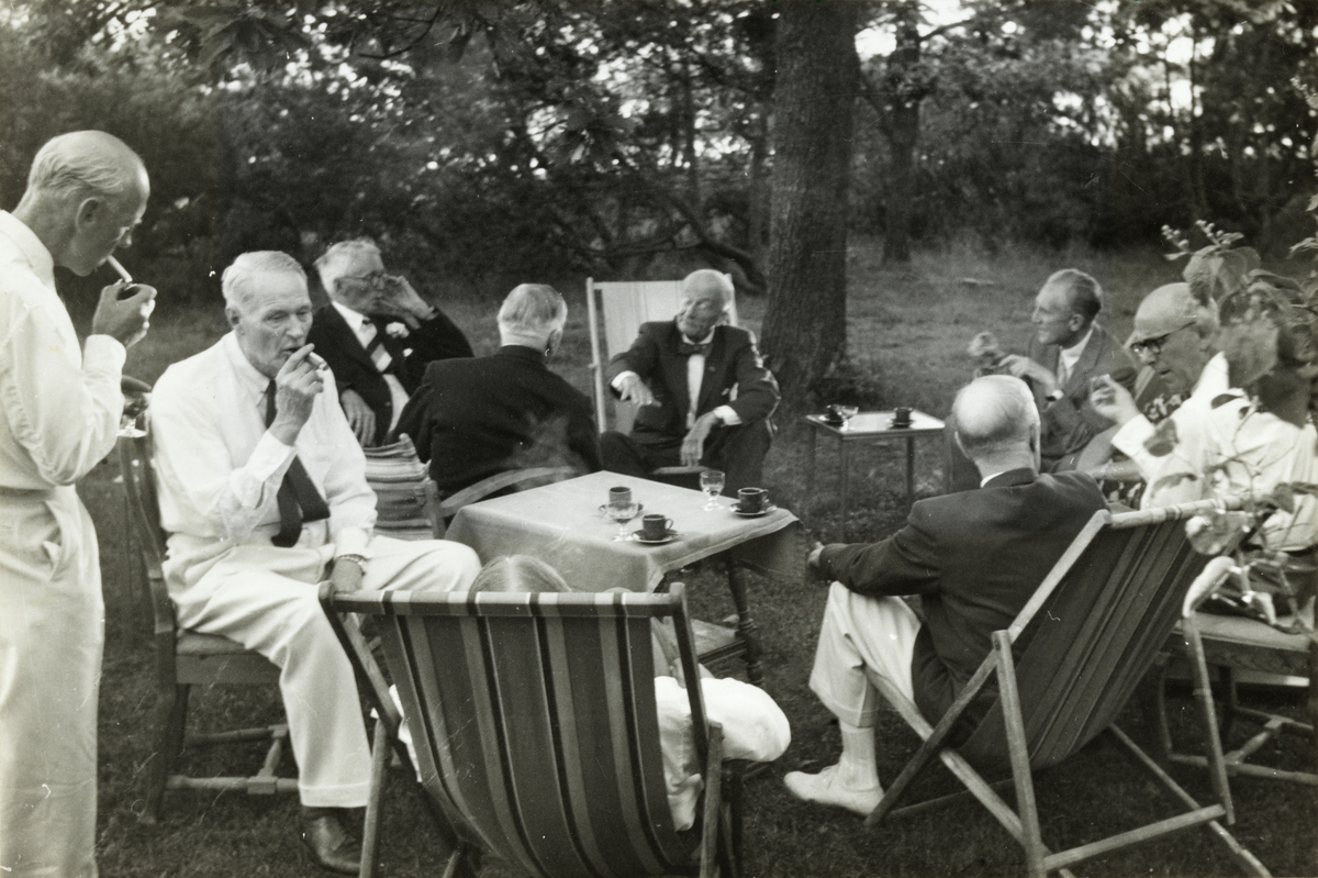 Medlemmer av skiklubben Fram feirer medlemmet Anders Beers 80-års dag på hans sommersted på Larkollen i Østfold. Fra venstre Nicolai Beer, Gerhard. C. Kallevig , Anders Beer, Fritz Treschow med ryggen til fotografen, Thomas Fearnley, Einar Trumpy, Arne Meidell og Westye P. Egeberg med ryggen til. Fotografert juli 1955.