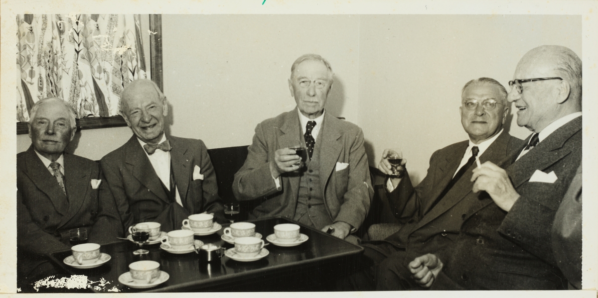  Medlemmer av skiklubben Fram sitter rundt et kaffebord med café avec. Medlemmer av skiklubben Fram. Fra venstre Fritz Treschow, Adolf Eger, Westye Parr Egeberg, ukjent og N.O. Young Fearnley. Fotografert juni 1957.
