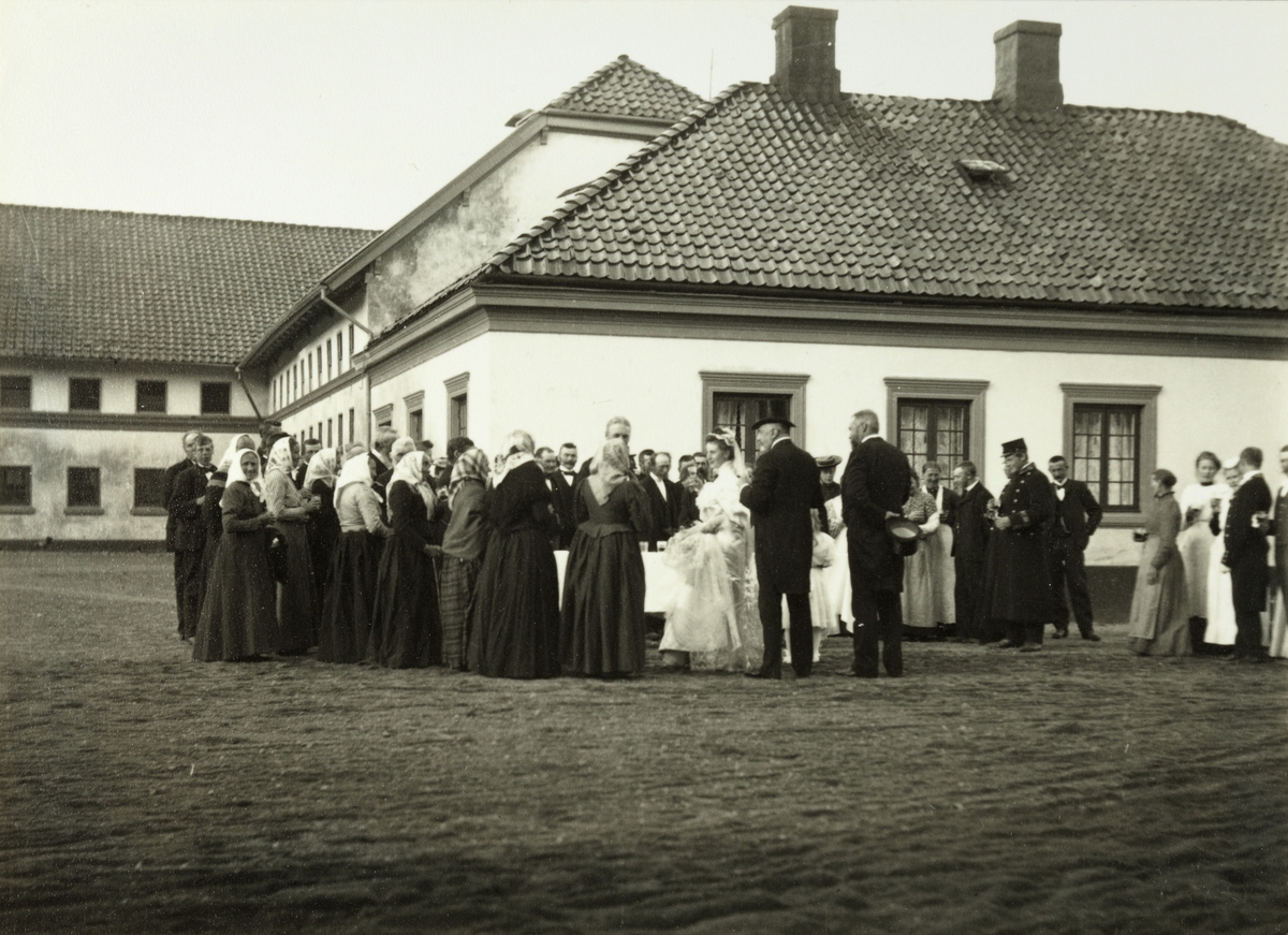 Brudeparet Nini, f. Wedel Jarlsberg, og Westye Parr Egeberg møter de ansatte på gårdsplassen til Bogstad gård. Til høyre for brudeparet står brudens far og eier av Bogstad gård, Herman Wedel Jarlsberg og noen av bryllupsgjestene. Fotografert 17. september 1904.