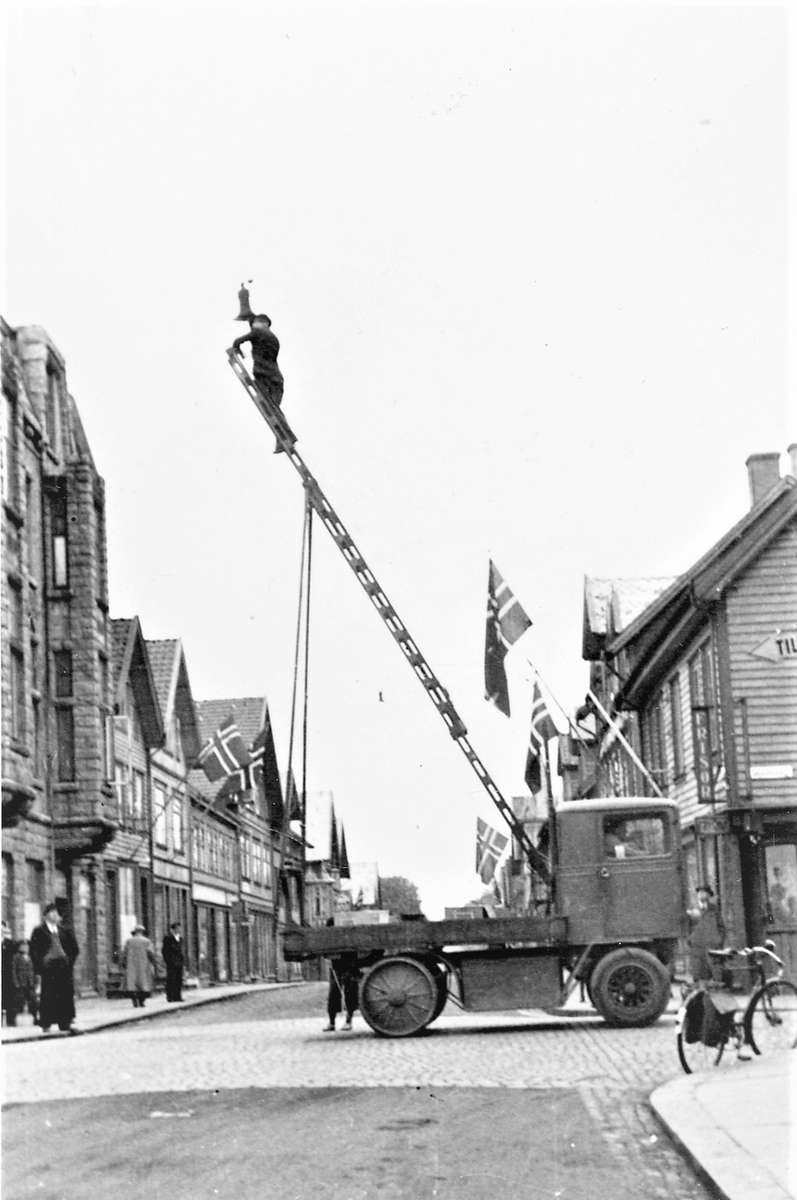 Feiring av freden 1945. Strandgaten, kveldstid 7. mai; folk fra Elektrisitetsverket skifter ut blendingspærene med ordinære lyspærer.