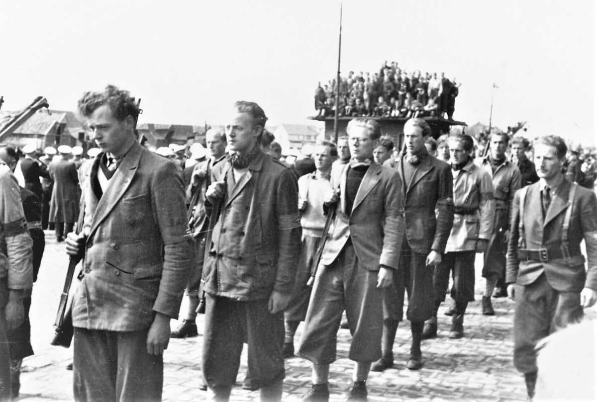 Feiring av freden 1945. Hjemmefronten deltar i mottagelsen av de britiske styrkene 15. mai , her marsjerer de sydover på indre kai. Tilskuere følger med.