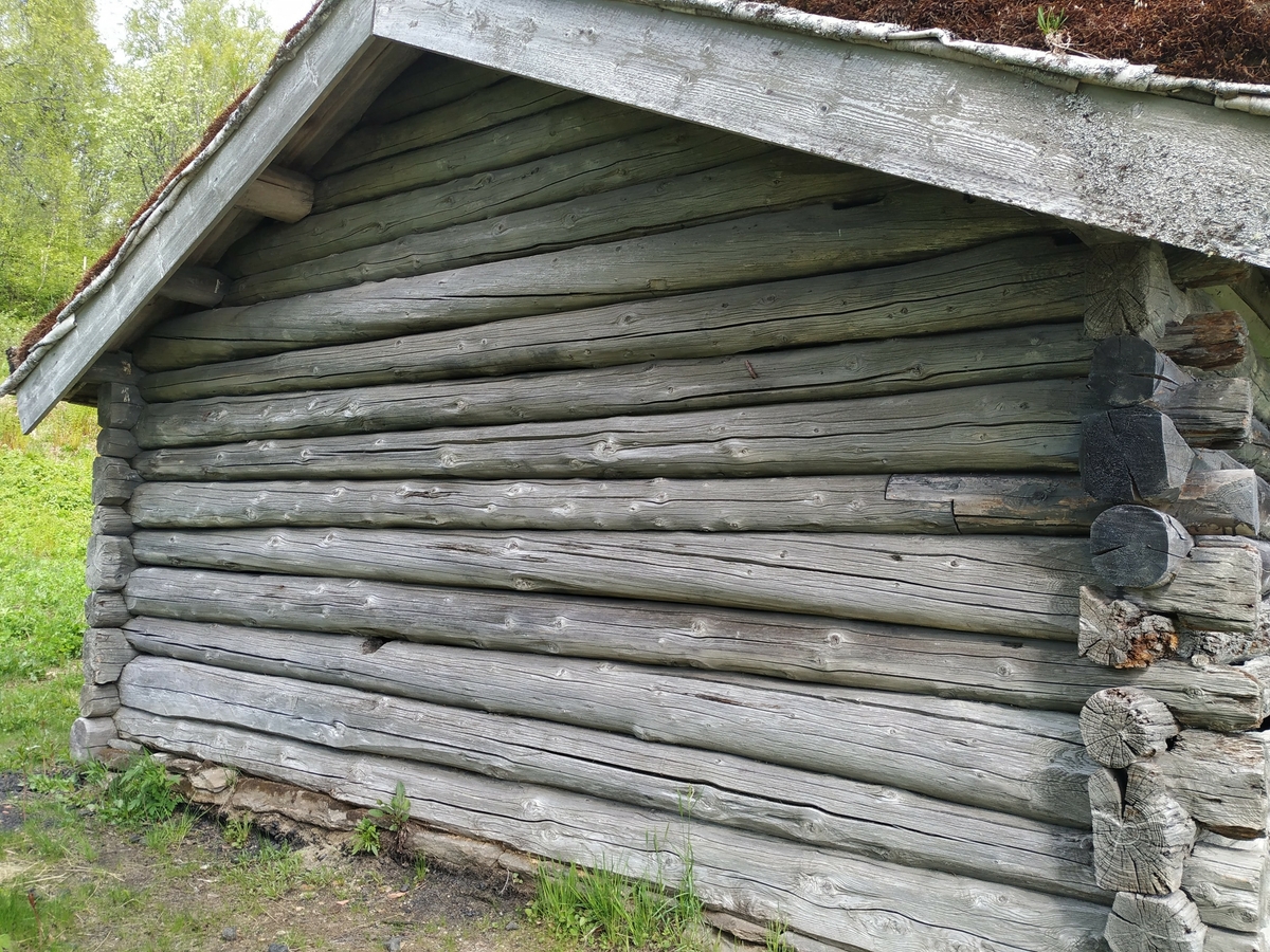 Laft rundtømmer uten meddrag. Steinmur og torvtak.