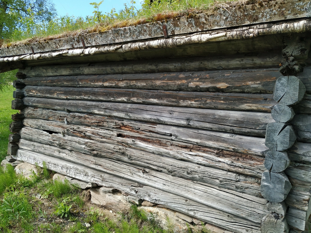 Laft rundtømmer uten meddrag. Steinmur og torvtak.