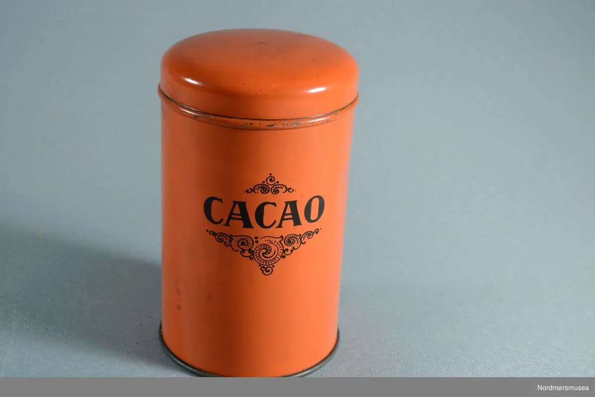 3 bokser til kaffe, te og kakao. Boksene er runde med flat bunn og buet lokk
Dekor: Skrift trykt i sorte bokstaver. Boks a: Kaffe, Boks b: Cacao, Boks c: The