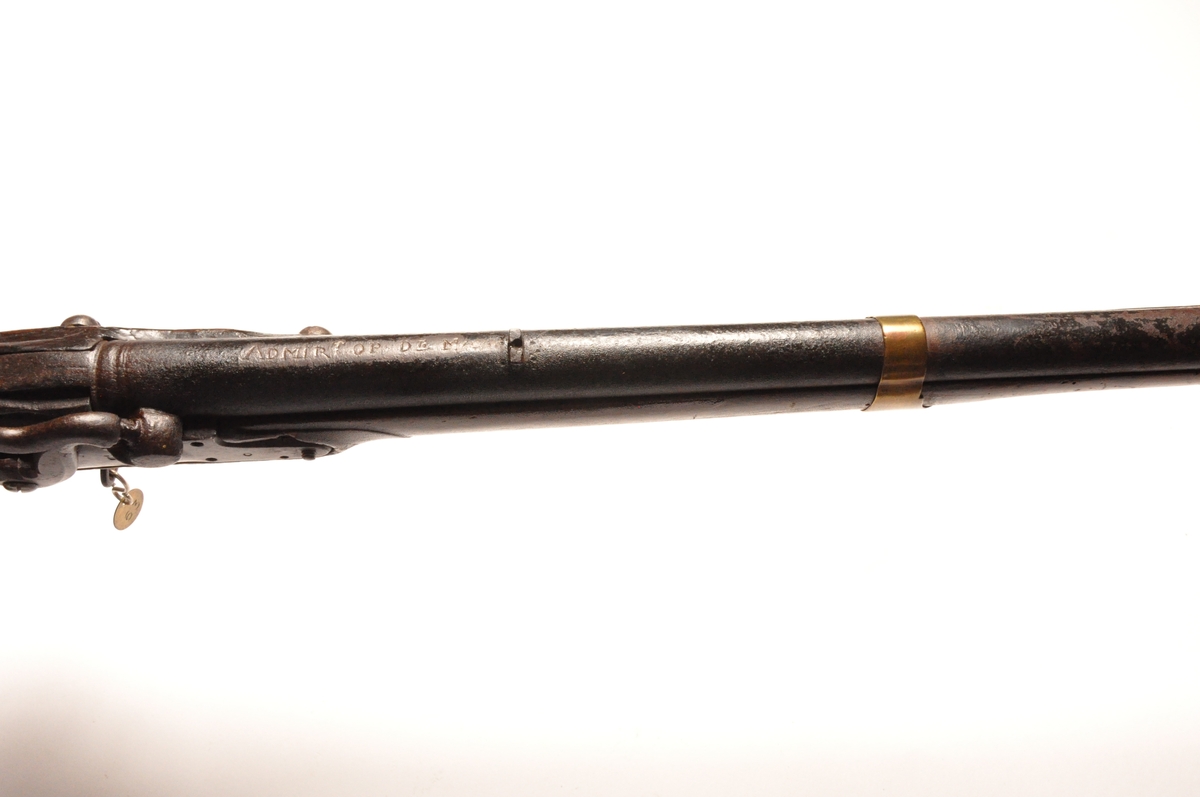 Glattløpet perkusjongevær av tre og metall med messingdetaljer. Flere innrissede merker og nummereringer. Opprinnelig militærvåpen.