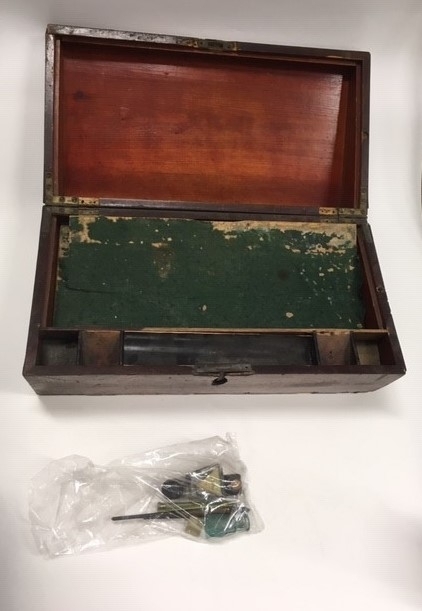 Reiseskrivebord i tre, mahognifinèr, skriveplate med grønn filt. Inneholder 3 blekkhus, 3 penner med pennespiss, 1 mekanisk blyant, 1 frimerke. Ang. tilhørt Oscar Borg.