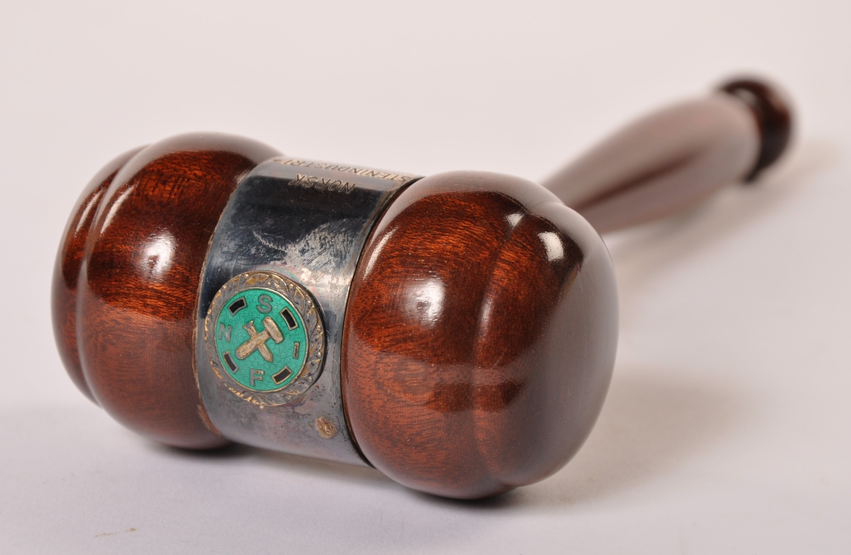 Styreklubbe i dreid, lakkert tre, beslått med metall og et emaljert merke. I pappeske (m/bomull) merket Gullsmed G. Langthon, Mysen.