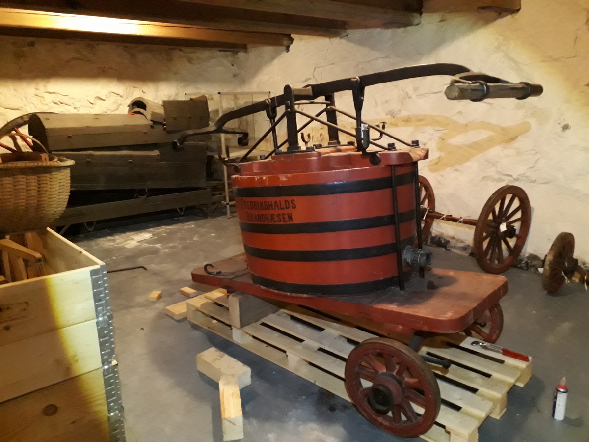 Pumpevogn i rødmalt tre med 4 jernbeslåtte hjul med drag til hest. På vogn montert tønne av rødmalt tre med pumpesystem for håndpumping. Ved pumpe flere bøyler for oppbevaring av brannutstyr. Tønne er belått med kobber på innside. Trekasse rundt pumpehus i tønna.