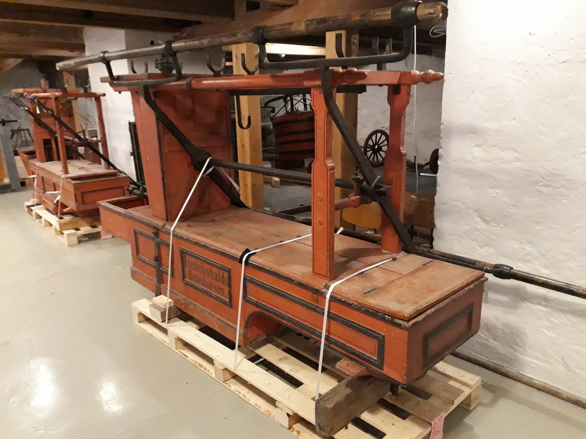 Pumpevogn av rødmalt tre med 4 jernbeslåtte hjul og drag til hest. Avlang kasse med lokk som inneholder pumpehus i metall. Rom foran, med lokk,  og bak, rommet bak har kran av messing som kan kobles til slange. Oppheng og bøyler med 2 slanger i tekstil, forsterka med metall. Langsgående pumpeanordning for håndpumping.