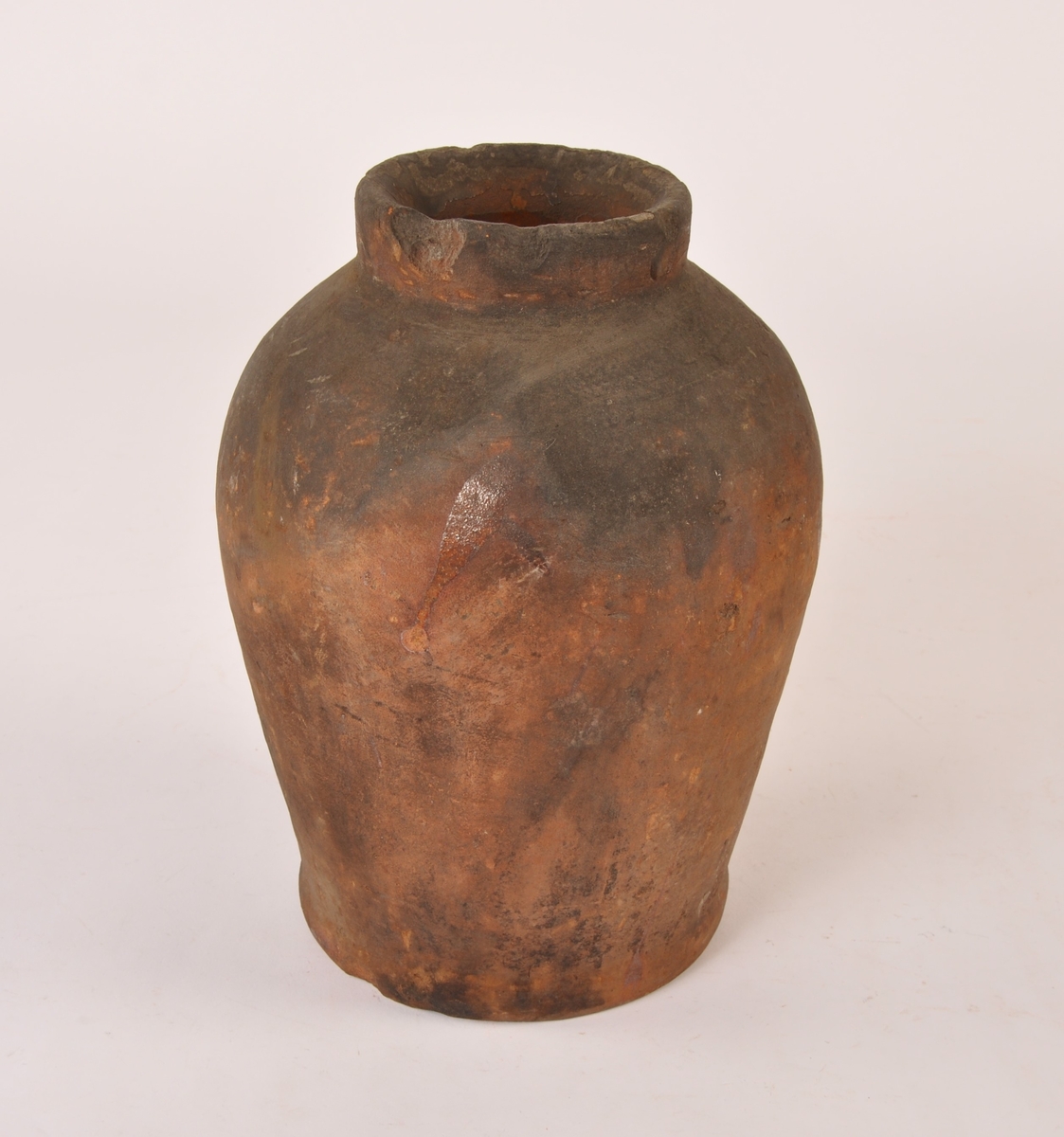 Dreid krukke i keramikk med fotrand og munningsrand. Sylinderformet med bredere form opp mot munningen. Noen glasurrester på utsiden. Glasert innside.