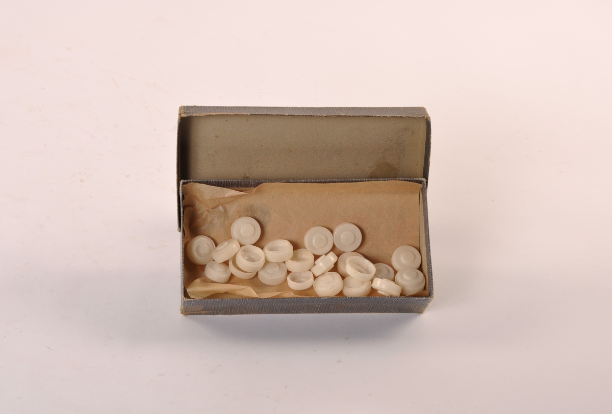 Eske av papp med lokk. Innehold: kapsler av porøst materiale.