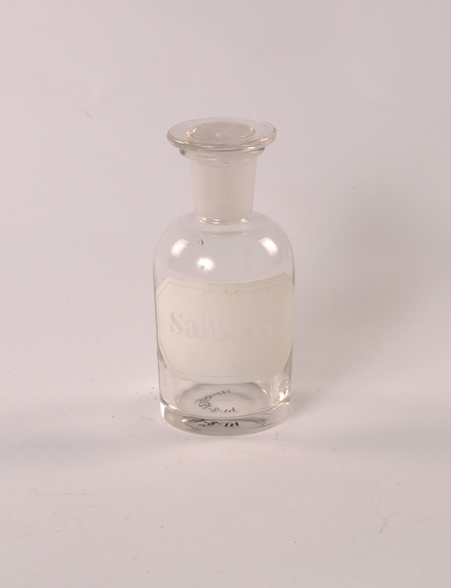 Flaske i klart glass. Rund form med smalere hals og munningsrand. Rund glasspropp.