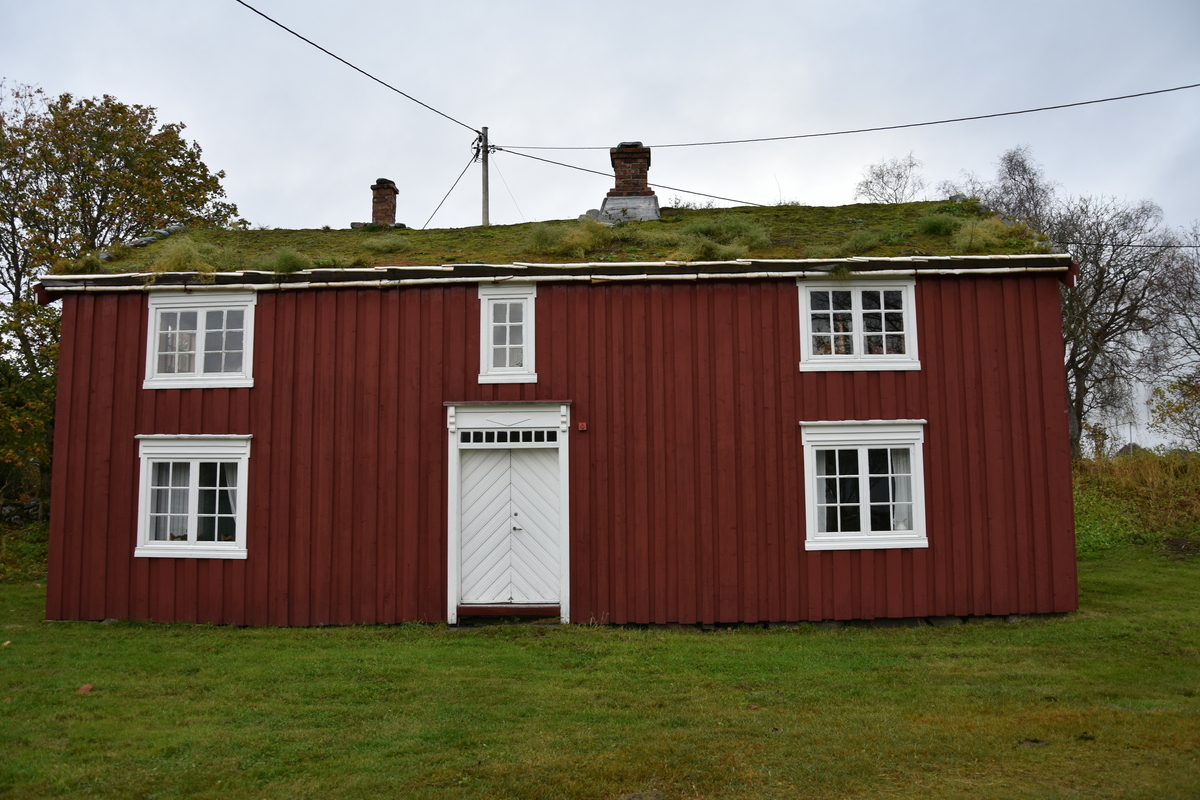 Laftet bygning med tømmermannskledning. Rødmalt med hvit kontrastfarge på omramminger.