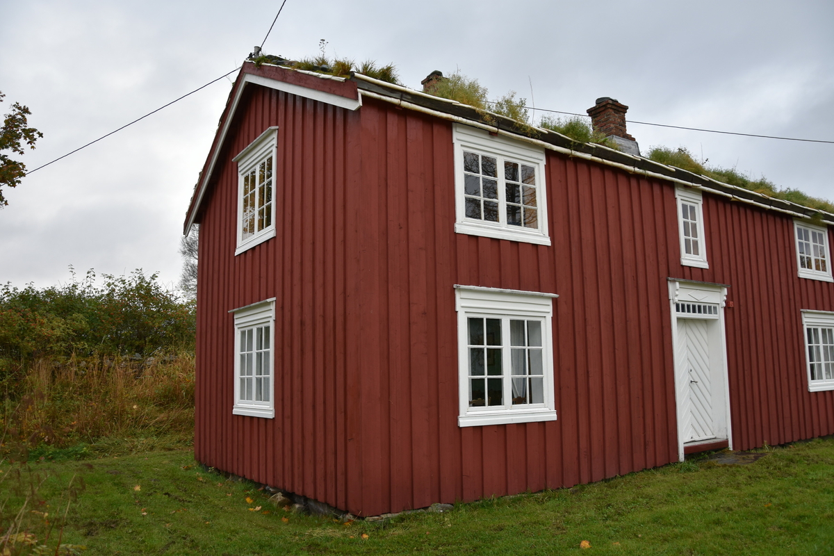 Laftet bygning med tømmermannskledning. Rødmalt med hvit kontrastfarge på omramminger.