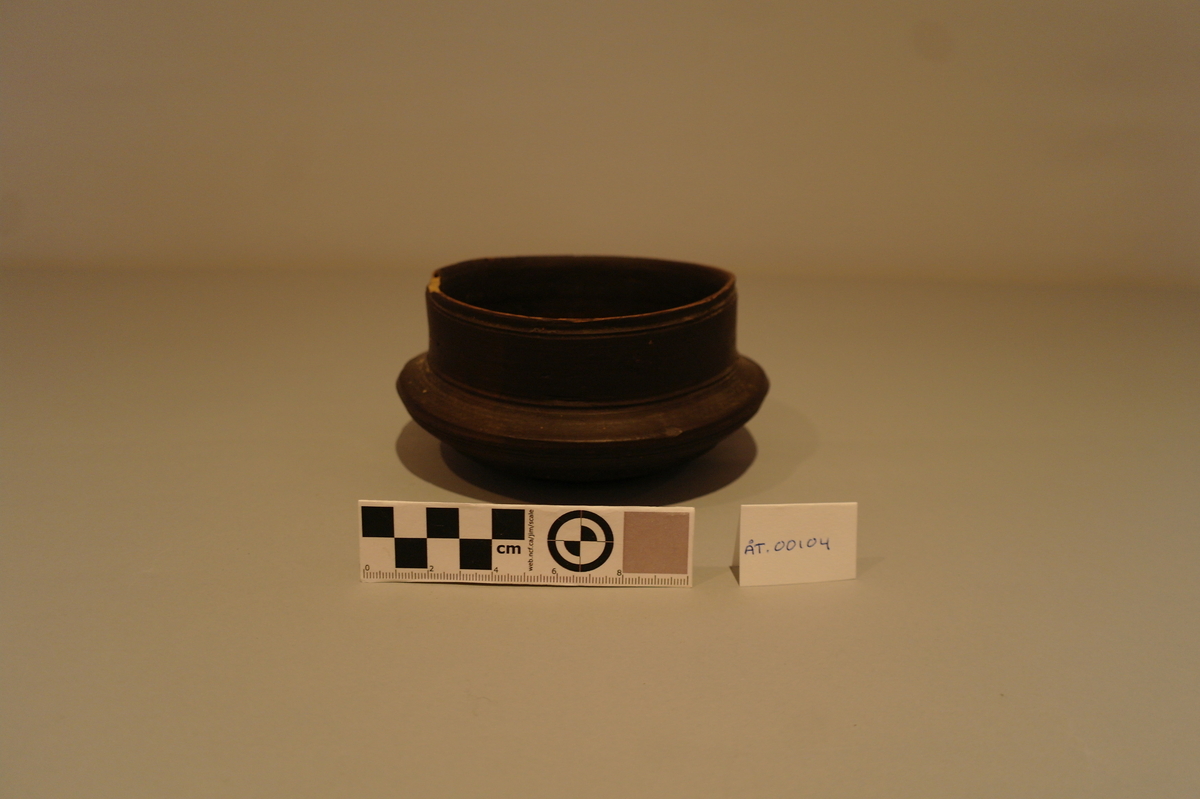 Brun dreiet bolle i tre. Sirkelforma munningsrand. Karet  svinger ut i ein vulst.  Eit lite hakk ved munningsranden.