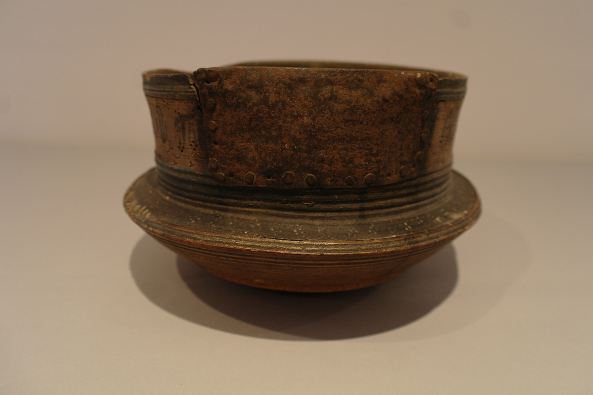 Dreiet bolle i tre. Sirkelforma munningsrand. Munningsranden er reparert med ein klinka plate av jarn. Bollen er måla med oker, svart, raud og blå. Den er dekorert med sviornamentikk og påmåla tekst.