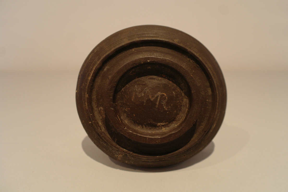 Brun dreiet bolle i tre. Sirkelforma munningsrand. Karet  svinger ut i ein vulst.  Eit lite hakk ved munningsranden.