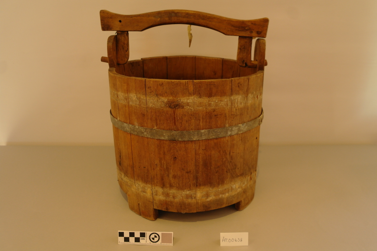 Bøtte med hank lagga av 14 stavar og haldt saman av eit sinkband. Eit sinkband manglar. Det er eit hol i kvart øyre kor tappane av hanken er festa. Tre av stavane er forlenga til føter. I god stand.