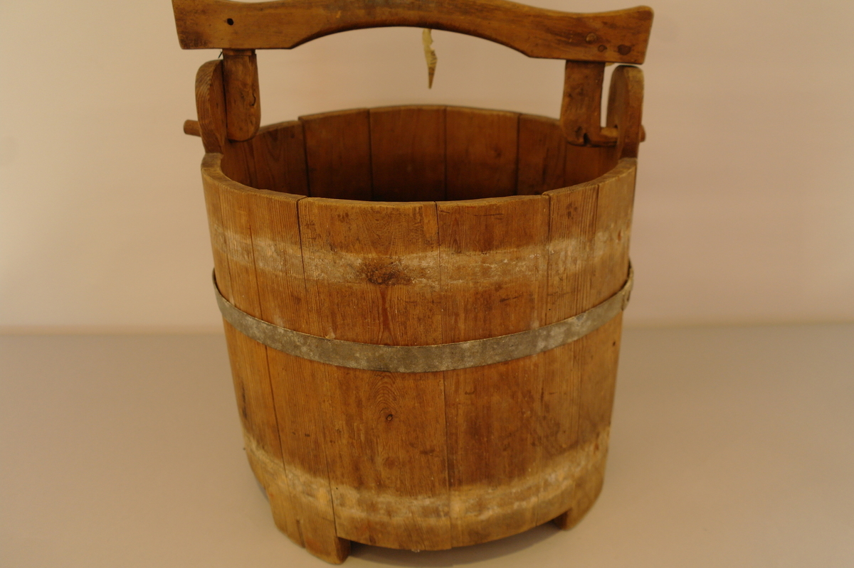 Bøtte med hank lagga av 14 stavar og haldt saman av eit sinkband. Eit sinkband manglar. Det er eit hol i kvart øyre kor tappane av hanken er festa. Tre av stavane er forlenga til føter. I god stand.