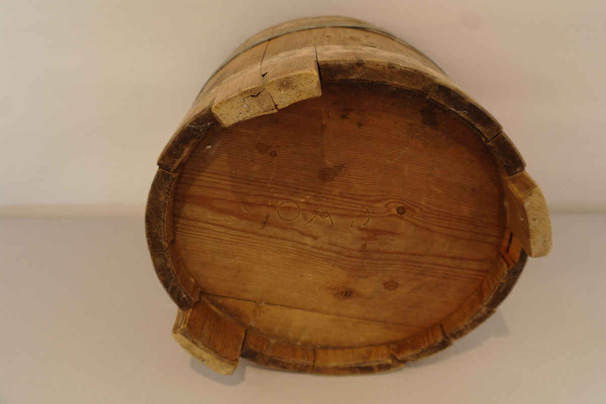 Bøtte med hank lagga av 14 stavar og haldt saman av eit sinkband. Eit sinkband manglar. Det er eit hol i kvart øyre kor tappane av hanken er festa. Tre av stavane er forlenga til føter. I god stand.