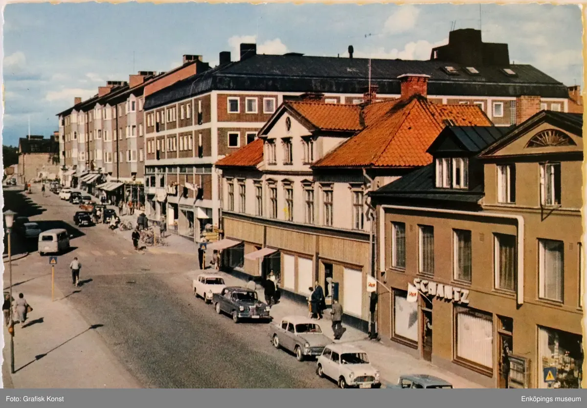 Kungsgatan vid Stora torget, Enköping, tidigt 1960-tal.

Husen närmast i bild revs när PAUS-huset byggdes. PAUS-huset stod färdigt 1971.