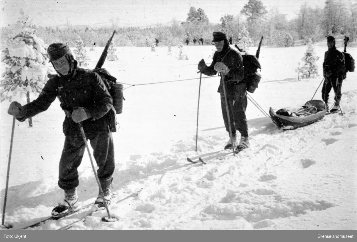 Soldater på ski i vinterlandskap. Den ene trekker en pulk. 