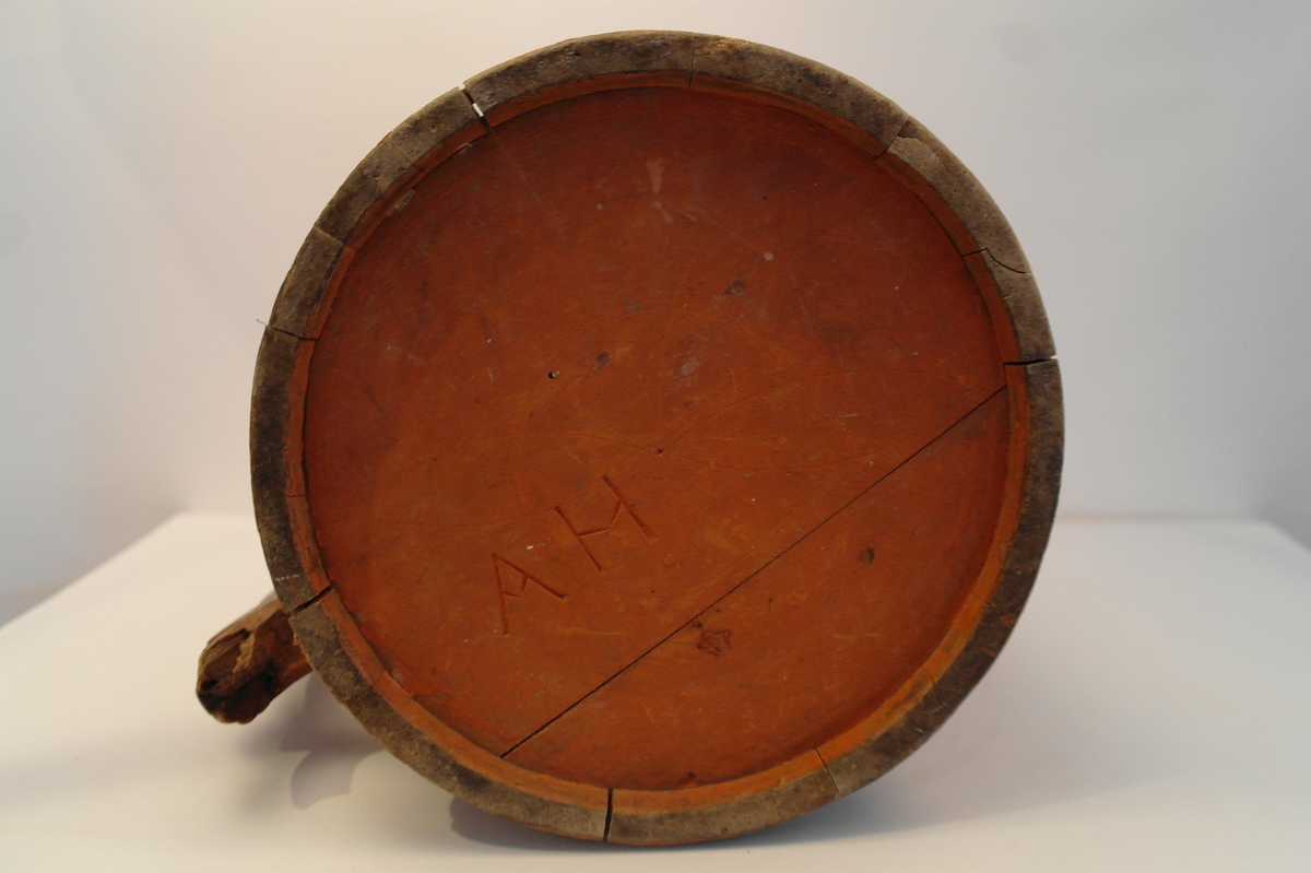 Lagga kar holdt saman av tre sinkband. Hanken er skrudd fast. Loket er hengsla til hanken med ein tretapp. Stavane, hanken og loket er dekorert med innrissa border,sirkler, spekulasjer og små blomer. Hanken er skåre ut i ein dekorativ fasong. Kanna er målt i ein raudbrun farge. I god stand. Nokre få hol etter mit.