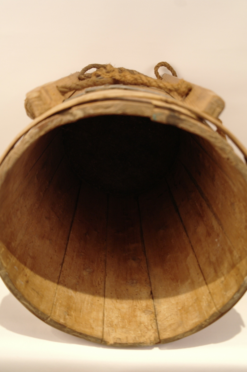 Ryggabøtte lagga av 12 stavar og haldt saman av 3 sinkband og eit laust treband på toppen. Sinkbanda er festa med spikrar. Stokkane til bæreanordningen er tappa fast til karet med trenaglar. To tau er festa til bæreanordningen. Sylindrisk. Hol etter mit, men ellers i god stand.