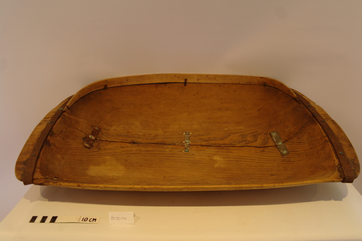 Trau i tre. Hola ut av eit stykke. Rektangulær og med runda buk. Handtaka på kortsidene er beslått med jarn. Ein stor sprekk går på langs frå handtak til handtak. Den er reparert med tre jarnbeslag. På den ene langsida er det satt på eit "skvettbord" festa med tau og spikrar.