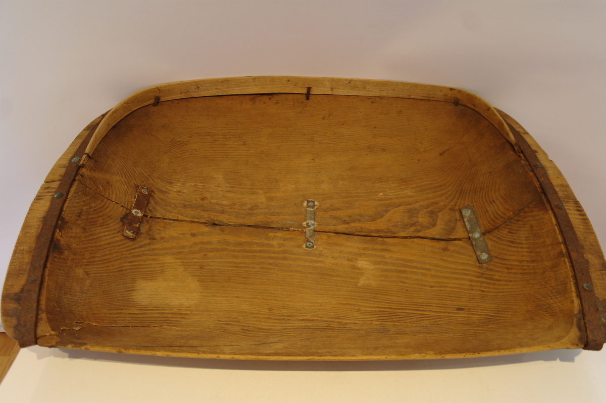 Trau i tre. Hola ut av eit stykke. Rektangulær og med runda buk. Handtaka på kortsidene er beslått med jarn. Ein stor sprekk går på langs frå handtak til handtak. Den er reparert med tre jarnbeslag. På den ene langsida er det satt på eit "skvettbord" festa med tau og spikrar.