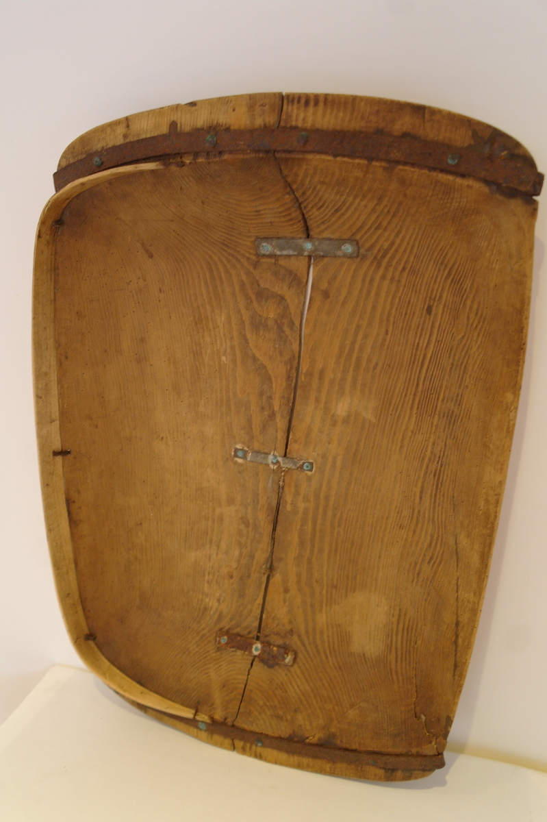 Trau i tre. Hola ut av eit stykke. Rektangulær og med runda buk. Handtaka på kortsidene er beslått med jarn. Ein stor sprekk går på langs frå handtak til handtak. Den er reparert med tre jarnbeslag. På den ene langsida er det satt på eit "skvettbord" festa med tau og spikrar.